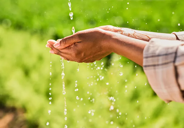 A person holding their hands out to collect falling water.