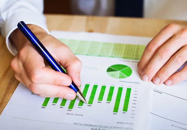 A person writing on a bar chart with a pen.