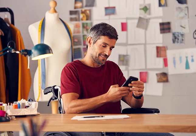 A man sitting at a desk looking at his phone.