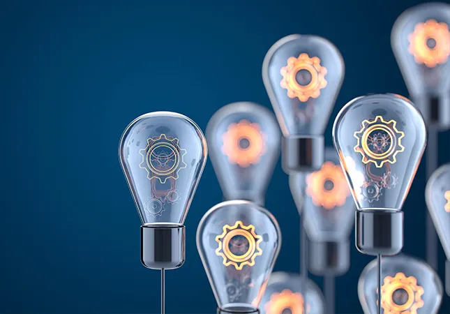 Several lightbulbs with glowing cogs inside of them.