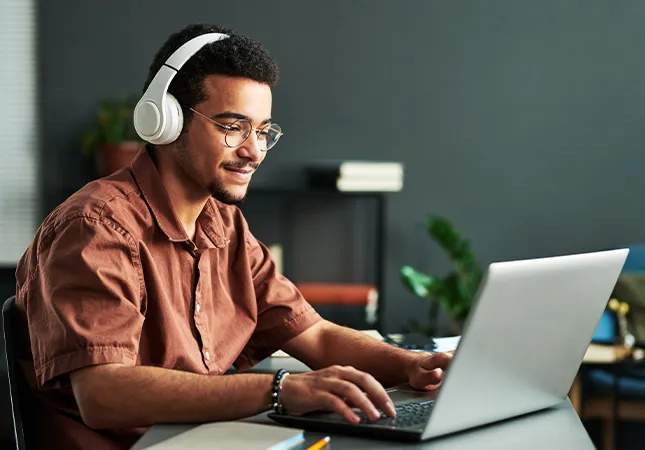 A man wearing headphones typing on a laptop.
