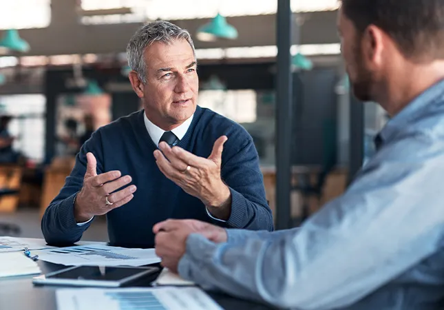 Two men discussing something at a table.