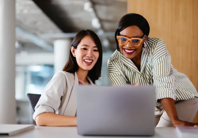 Two women looking at a laptop and smiling.