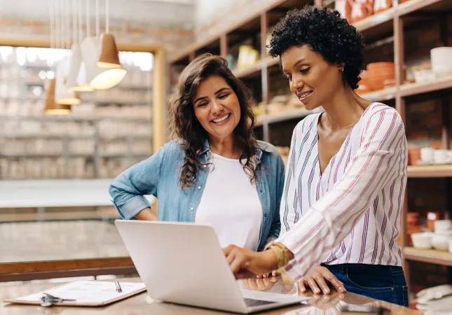 Two women looking at a laptop and chatting together.
