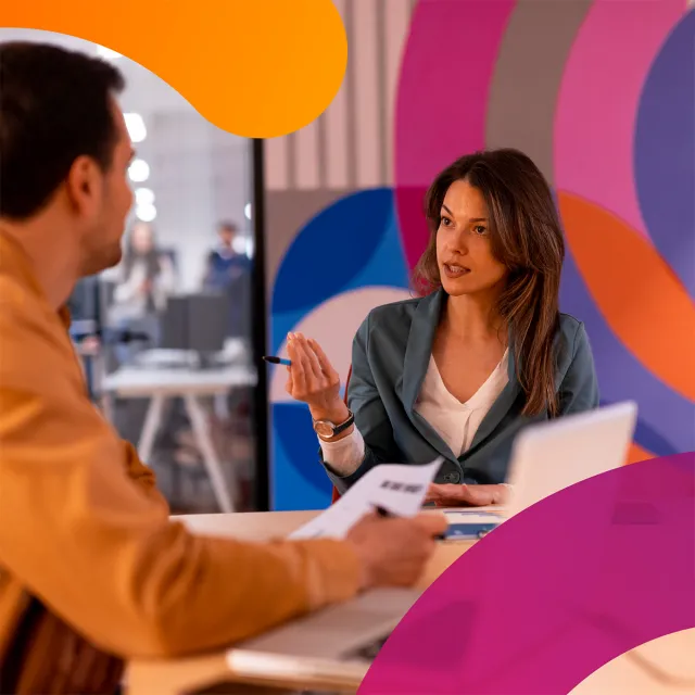 A man and a woman talking at a desk together.