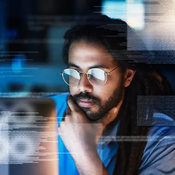 A person looking at a laptop screen with information emerging from the screen.