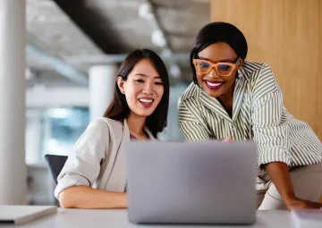 Two women looking at a laptop and smiling.
