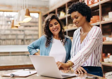 Two women looking at a laptop and chatting together.