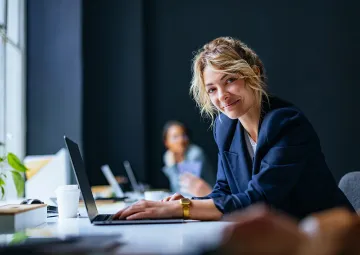 A woman using a laptop and smiling.