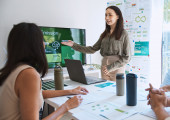 A woman pointing at a screen that displays information on carbon emissions.
